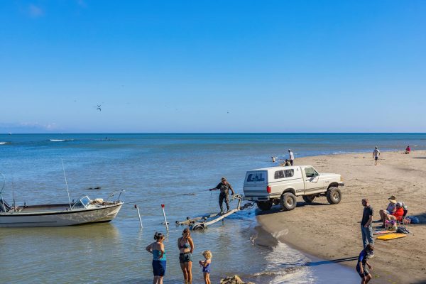 A Person Standing on Trailer Pulling a Boat on Body of Water